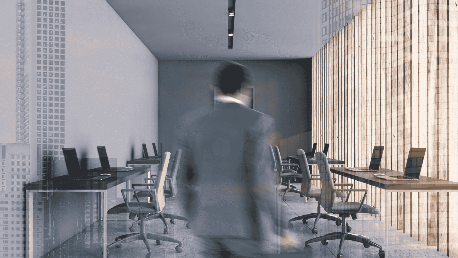 Blurry person walking through a modern glass-walled conference room with laptops on tables and city views outside